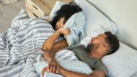couple in bed together; woman annoyed by snoring